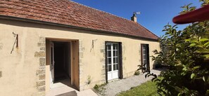 Un edifici amb teulada vermella, una xemeneia i un petit jardí amb grava i gespa.
