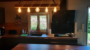 Et køkken med en stor ø, mikrobølgeovn, vask og et vindue med udsigt til grønne områder.