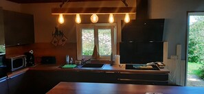 Eine Küche mit einer großen Kochinsel, einer Mikrowelle, einem Spülbecken und einem Fenster mit Blick auf Grünfläche.
