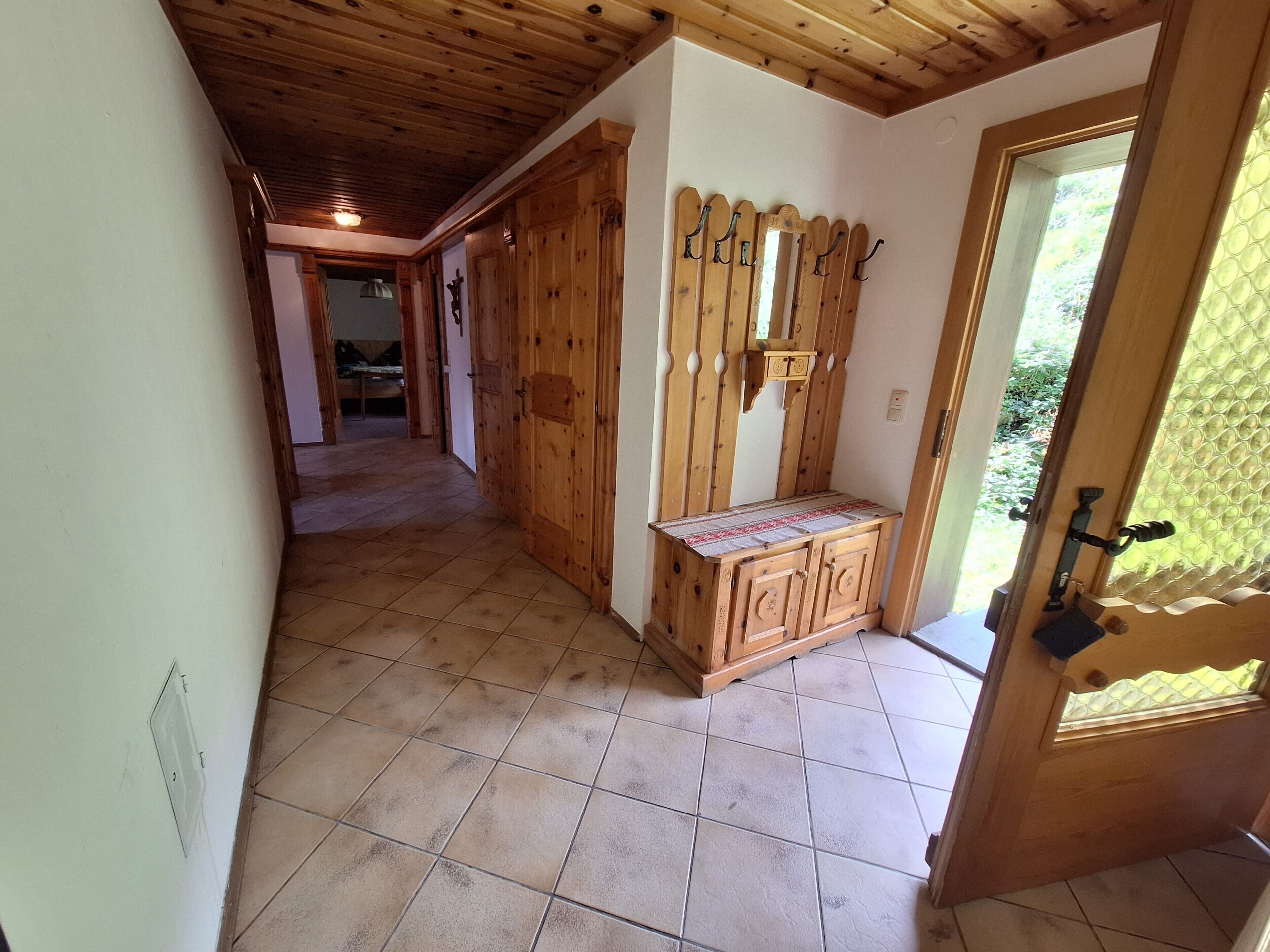 Un pasillo con puertas de madera, un banco y una puerta con panel de vidrio esmerilado.