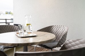 A round table with a metal base, a glass pitcher, and a tray with glasses and a plate. - Bright Beach-chair Baltic Suite (Lübeck)