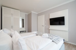 A hotel room with a bed, a wardrobe, a television, and a mirror. - Bright Beach-chair Baltic Suite (Lübeck)