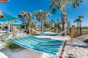 Une zone de plage avec des hamacs et des palmiers.