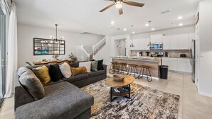 A modern living room with a gray sectional sofa, a coffee table, and a dining area with bar stools. - Sleeps 14 *Private Pool *Arcade Games *BBQ Grill (Davenport)