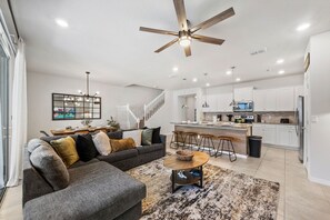 A modern living room with a gray sectional sofa, a coffee table, and a dining area with bar stools. - Sleeps 14 *Private Pool *Arcade Games *BBQ Grill (Davenport)