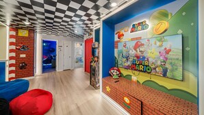 A room with a Nintendo-themed wall, a large screen displaying Super Mario characters, and a checkered ceiling. - Sleeps 14 *Private Pool *Arcade Games *BBQ Grill (Davenport)