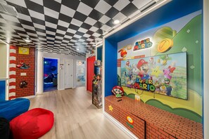 A room with a Nintendo-themed wall, a large screen displaying Super Mario characters, and a checkered ceiling. - Sleeps 14 *Private Pool *Arcade Games *BBQ Grill (Davenport)