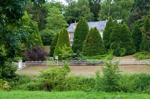A landscaped garden with neatly trimmed hedges and a white fence.