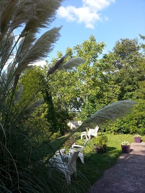 A garden with potted plants and white chairs.