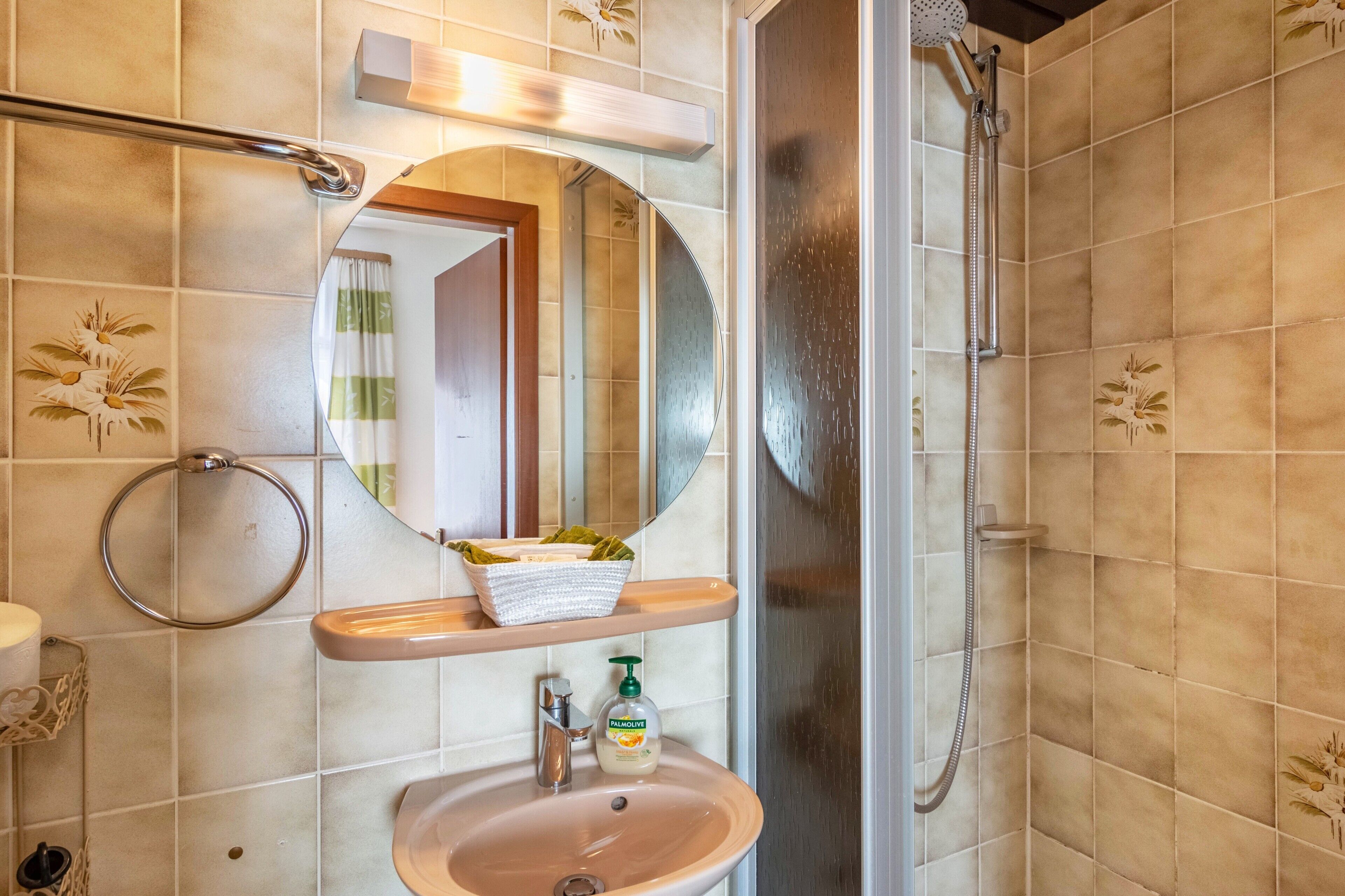 Ein Badezimmer mit Waschbecken, Spiegel, Handtuchhalter und Dusche.