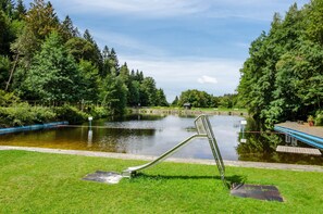A park with a pond, a metal slide, and a wooden deck. - Studio Apartment 'Haus Kuhlmann' with Shared Garden and Wi-Fi (Landkreis Goslar)