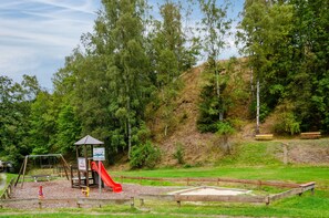 A playground with a slide, swings, and a small shelter. - Studio Apartment 'Haus Kuhlmann' with Shared Garden and Wi-Fi (Landkreis Goslar)