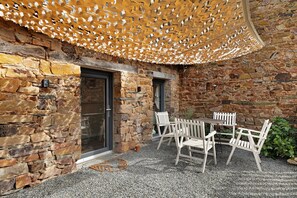 A stone building with a wooden table and chairs, a door, and a window.