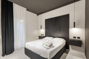 A modern hotel room with a large bed, white linens, a black headboard, and two bedside tables with lamps. - Bed and Breakfast 'Vicolo Del Fortino - Suite 101' with Balcony, Wi-Fi and Air Conditioning (Catania)