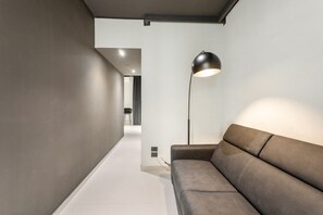 A modern interior with a sofa, a floor lamp, and a minimalist design. - Bed and Breakfast 'Vicolo Del Fortino - Suite 101' with Balcony, Wi-Fi and Air Conditioning (Catania)