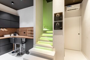 A modern kitchen with a wooden countertop, two bar stools, and a coffee machine. - Bed and Breakfast 'Vicolo Del Fortino - Suite 101' with Balcony, Wi-Fi and Air Conditioning (Catania)