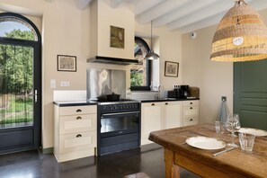 A modern kitchen with a stove, oven, and dining table set for two.