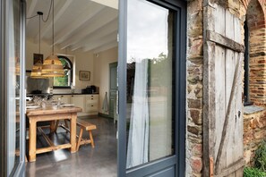 A modern kitchen with a dining area, large windows, and a stone exterior wall. - Le Grand Gîte: terrace, private garden & Wi-Fi on an organic farm in Grand-Fougeray (Grand-Fougeray)