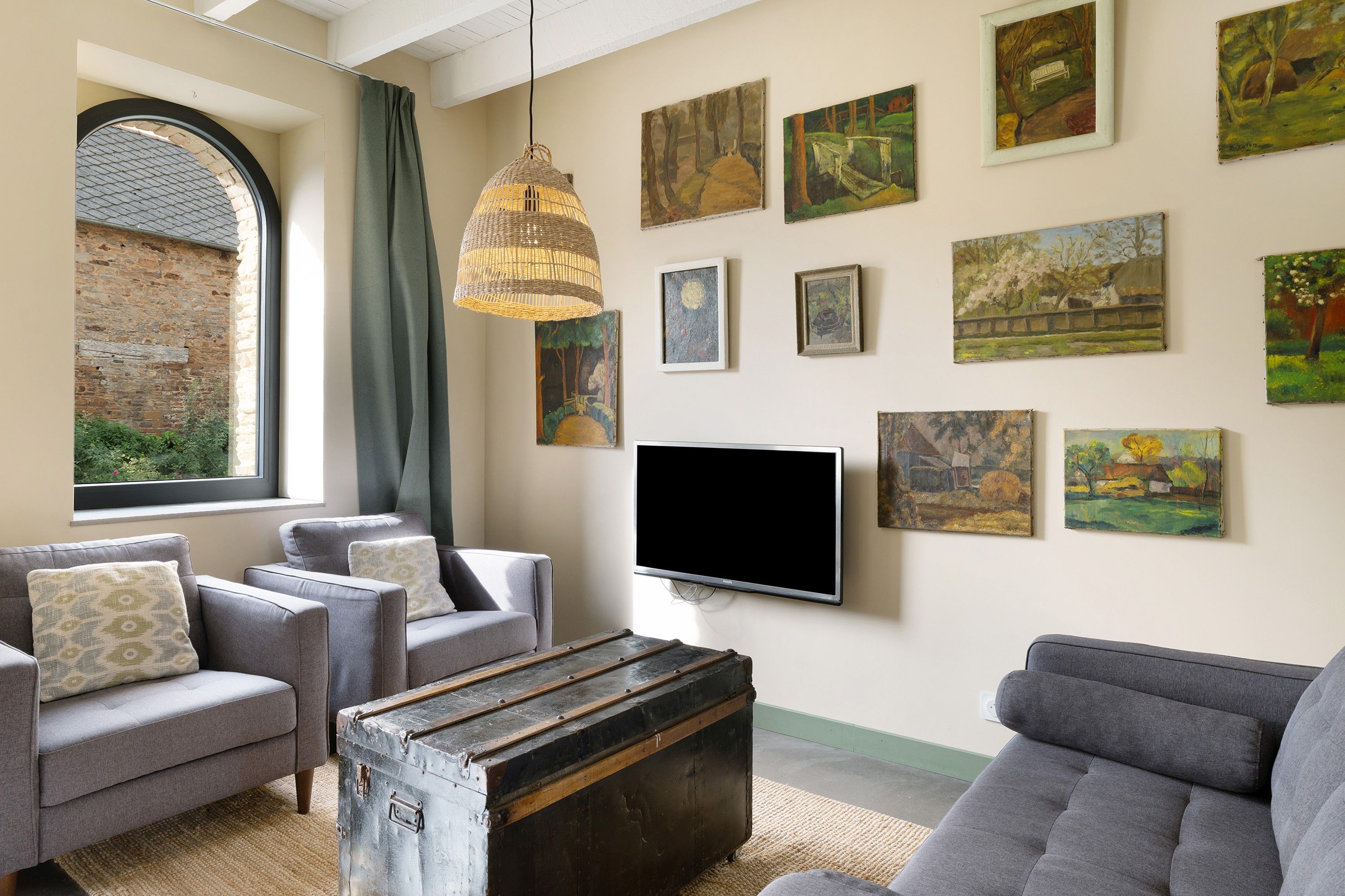 Ein Wohnzimmer mit einem großen Fenster, einem Fernseher und mehreren Bildern an der Wand.