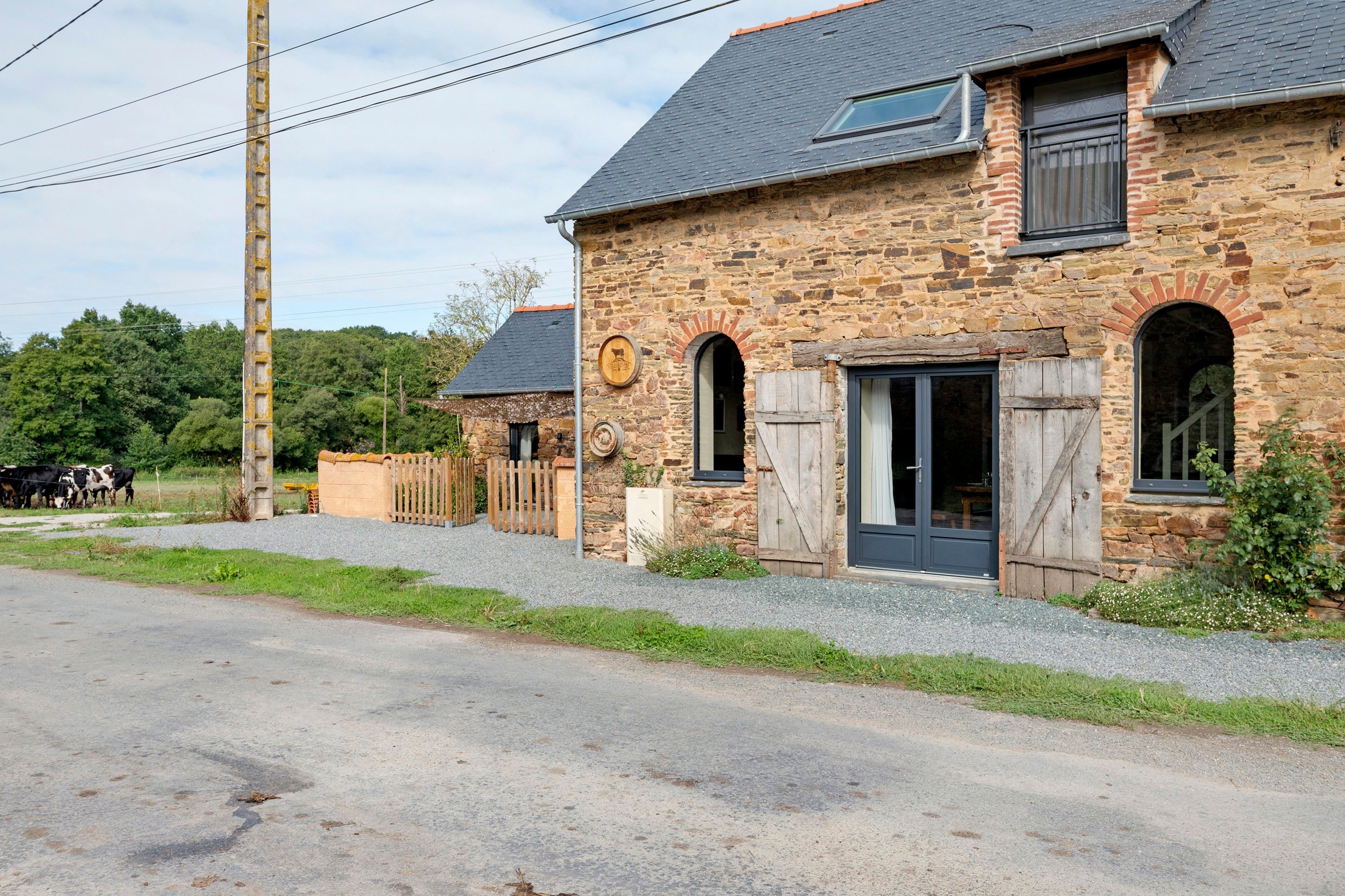 A stone building with a traditional design, featuring a wooden door, a window with shutters, and a small porch area.