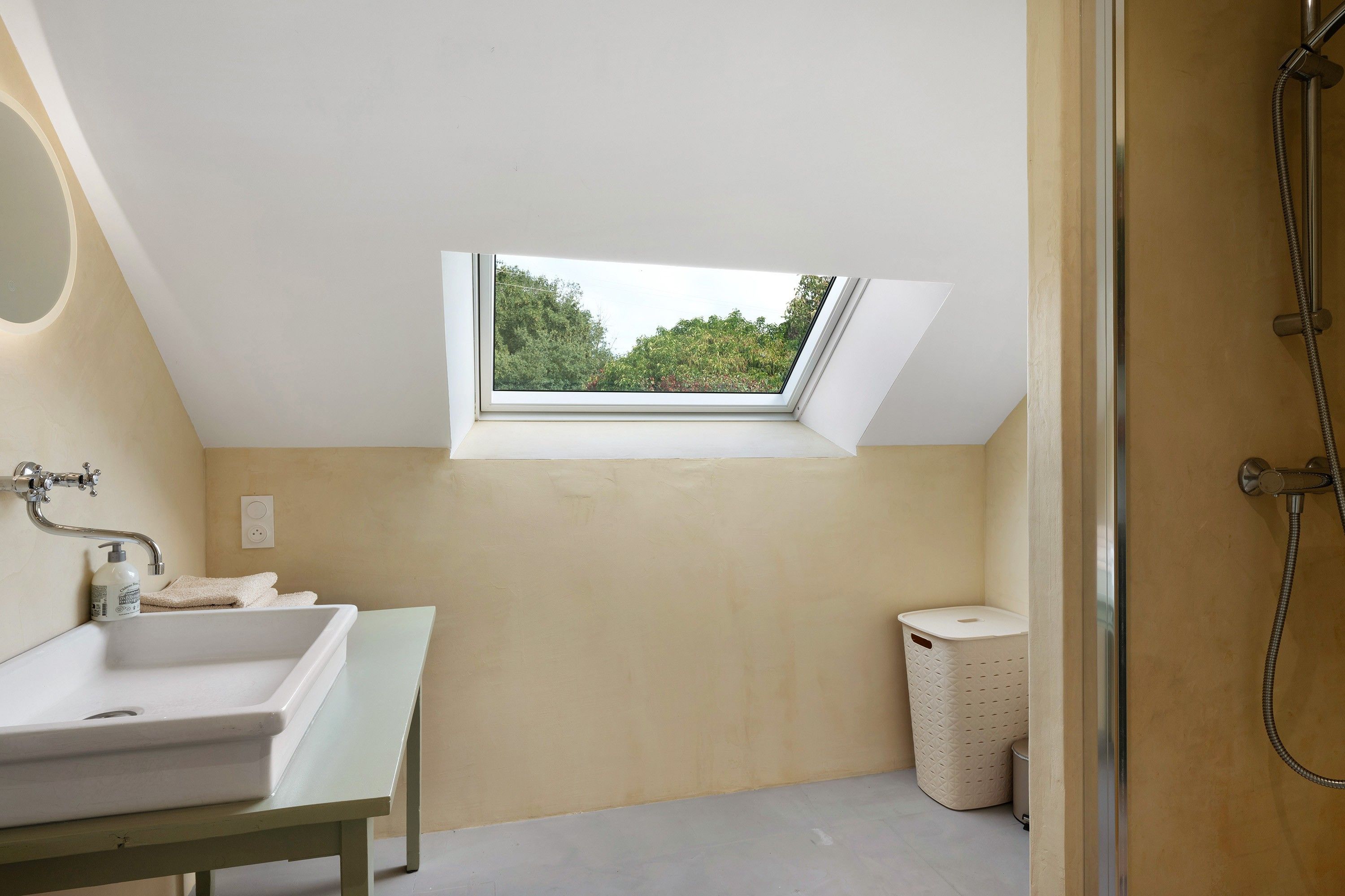 Een moderne badkamer met dakraam, bad, douche en toilet.