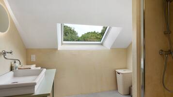 Een moderne badkamer met dakraam, bad, douche en toilet.