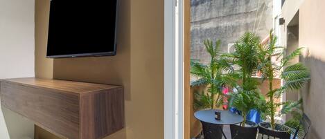 A modern living space with a mounted TV, a wooden cabinet, a small round table, and potted plants.