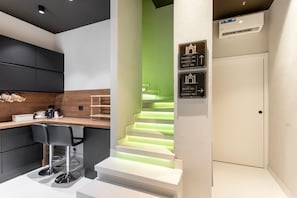A modern kitchen with a wooden countertop, two bar stools, and a coffee machine. - Bed and Breakfast 'Vicolo Del Fortino - Camera 103' with Balcony, Wi-Fi and Air Conditioning (Catania)