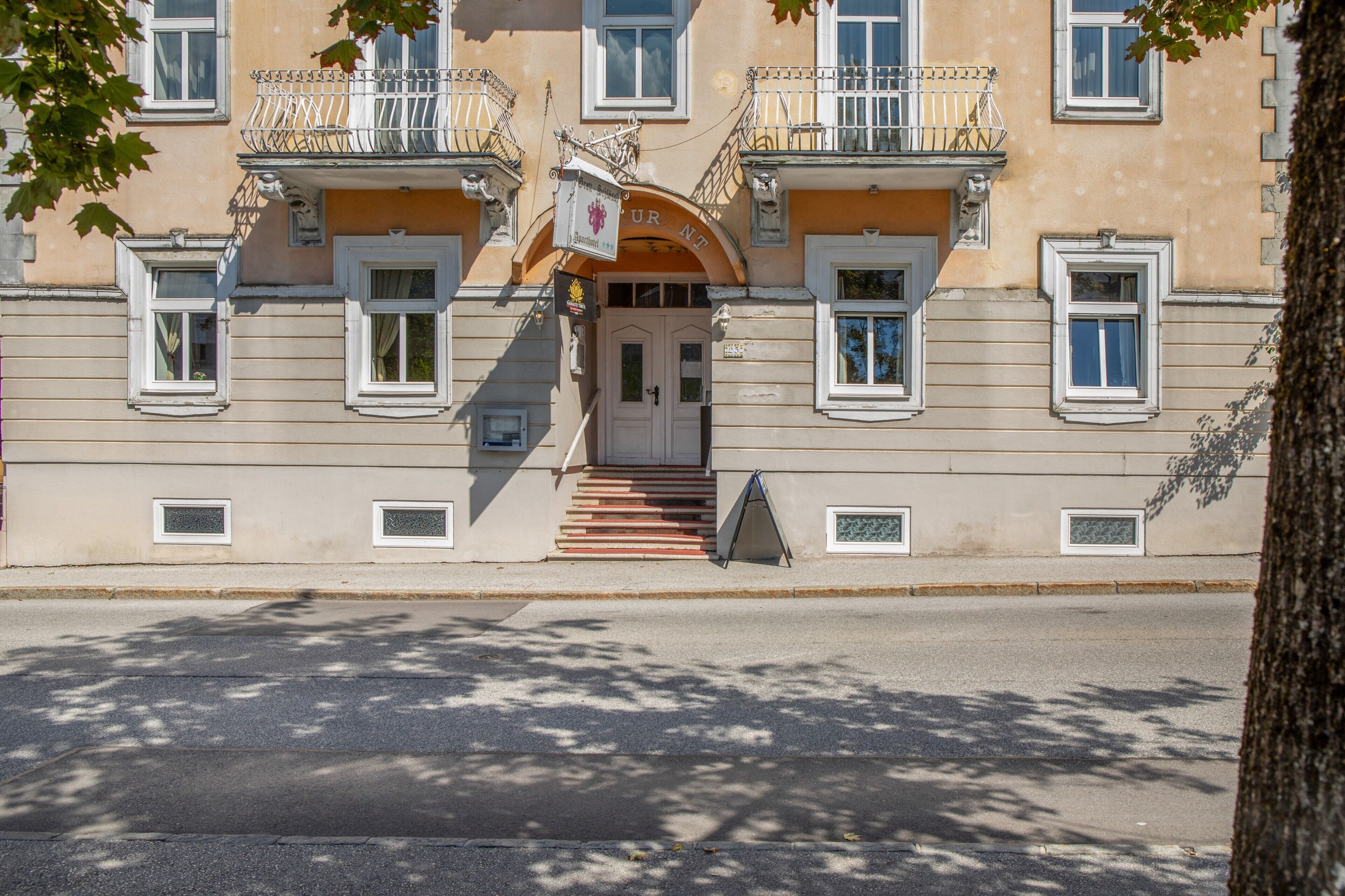 Un edificio con entrada central, varias ventanas y una escalera que lleva a la entrada.