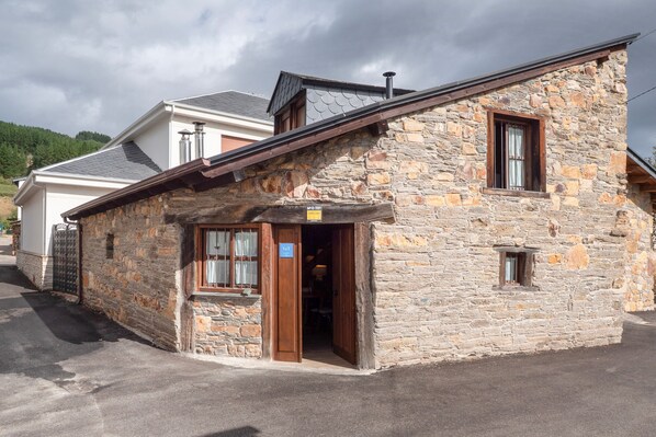 A stone building with a sloped roof, a wooden door, and a small window.