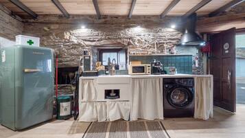 Cocina rústica con lavadora, microondas y refrigerador.