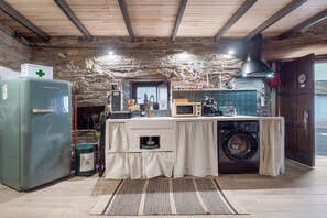 Cocina rústica con lavadora, microondas y refrigerador.