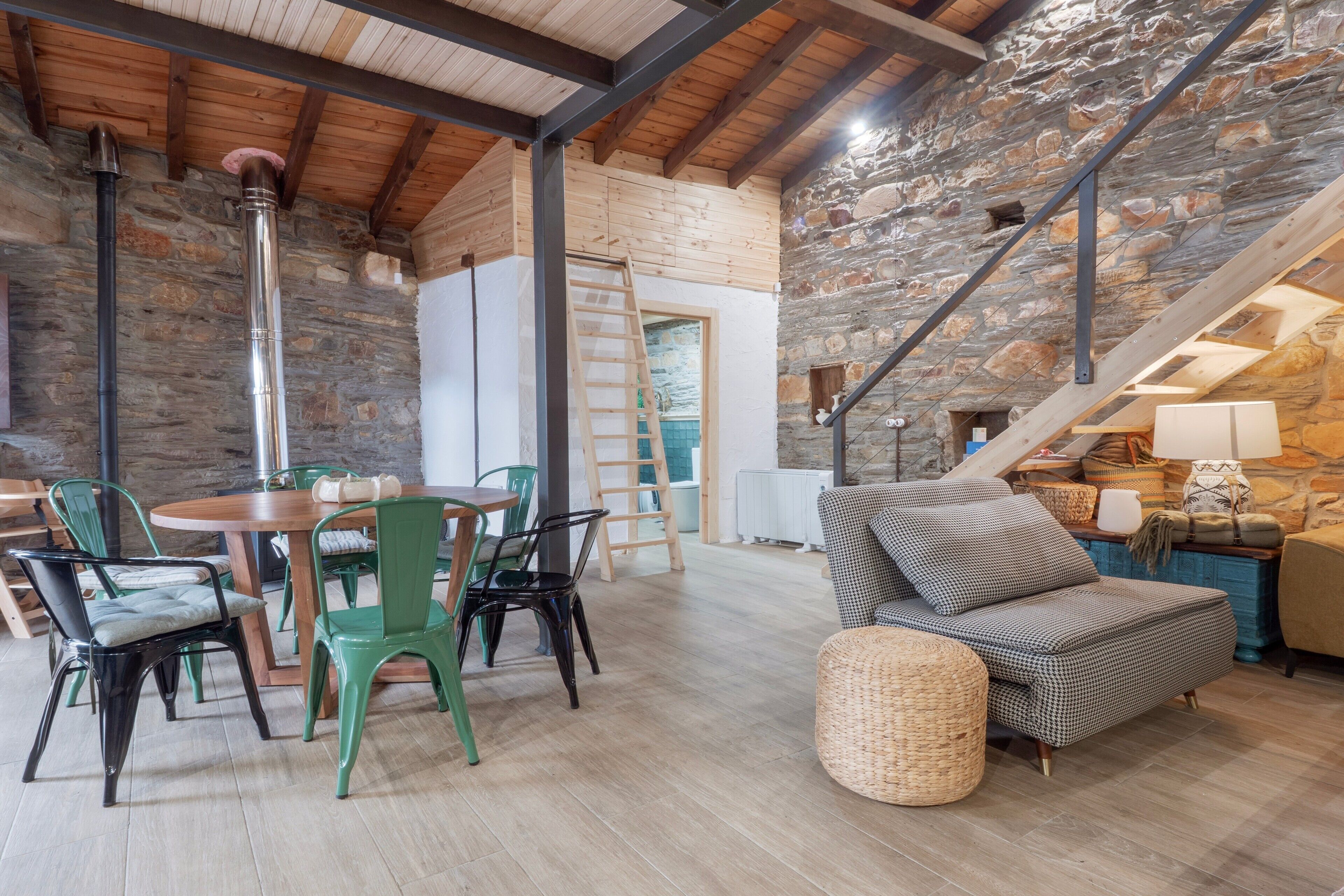 Un intérieur rustique avec une table à manger en bois, des chaises, un canapé et un mur en pierre.
