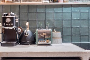 A kitchen counter with a coffee maker, a kettle, a toaster, and a sugar container.
