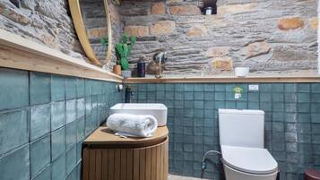 A bathroom with a stone wall, a sink, a toilet, and a mirror.