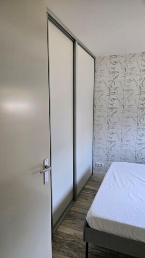 A bedroom with a bed, a wardrobe, and a patterned wallpaper. - Eendje 1 | Vrijstaande 6-persoons vakantiewoning (Ermelo)