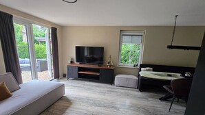 A modern hotel room with a large bed, a sofa, a TV, and a desk. - Eendje 1 | Vrijstaande 6-persoons vakantiewoning (Ermelo)