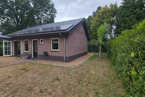 Et et-plans murhus med skråt tag, en hoveddør og en lille forhave med en grussti.
