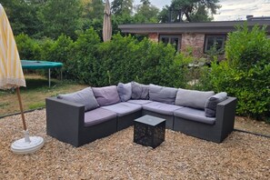 En modulsofa med puder, et lille bord og en parasol.