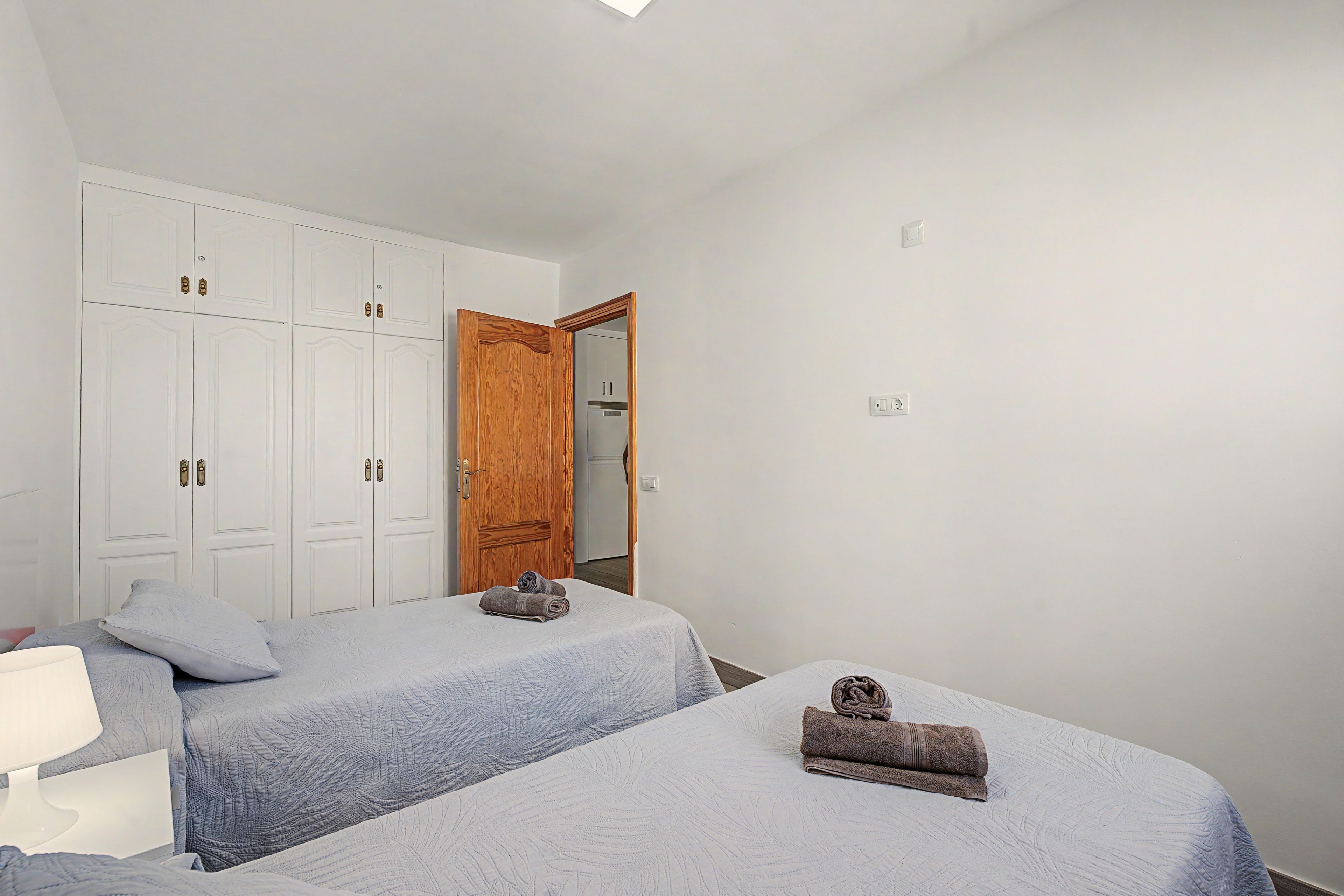 A bedroom with two beds, a wardrobe, and a mirror.
