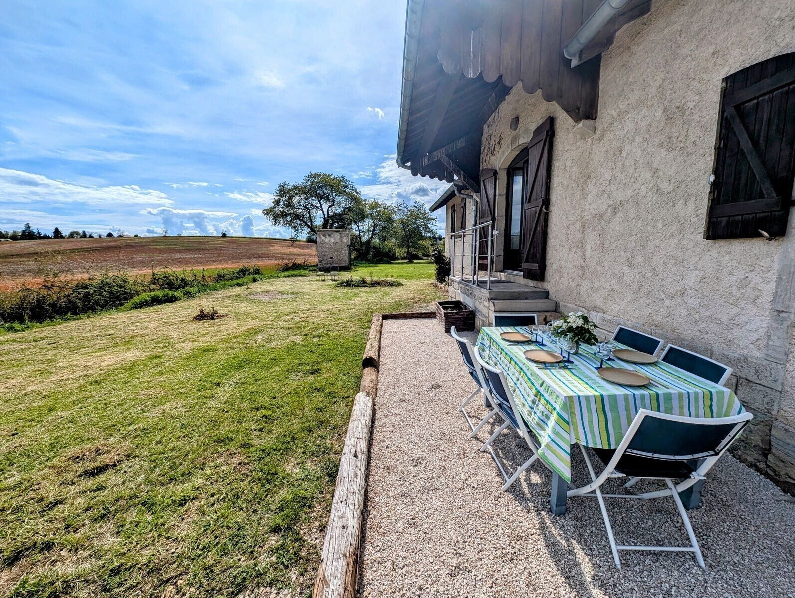 Een terras met een eettafel, een stenen muur en uitzicht op het landschap.