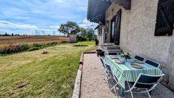 Een terras met een eettafel, een stenen muur en uitzicht op het landschap.