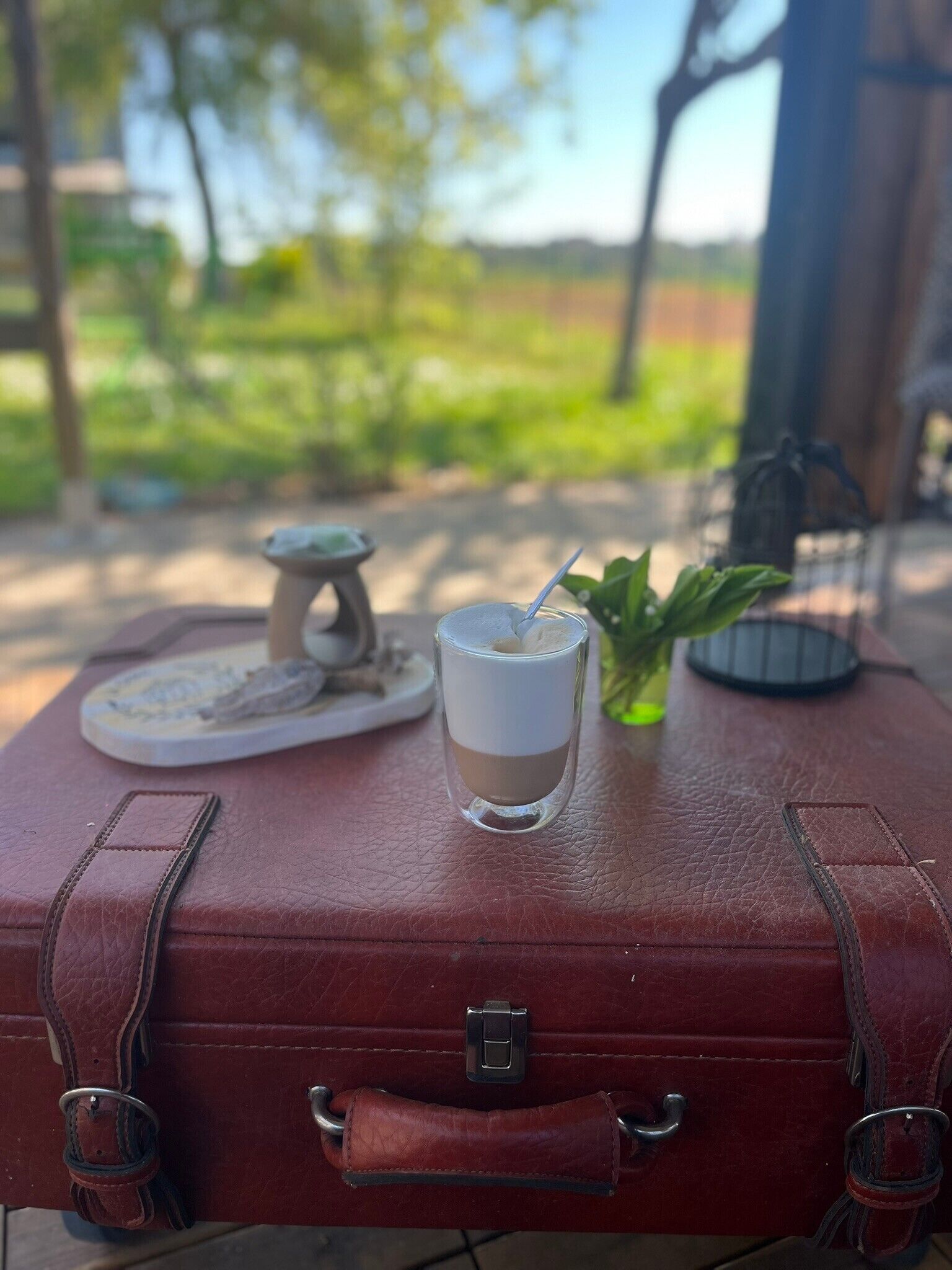 A suitcase with a drink and a candle on top.