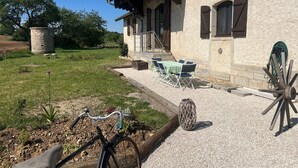 A rustic building with a stone exterior, a gravel patio, outdoor seating, and a bicycle.
