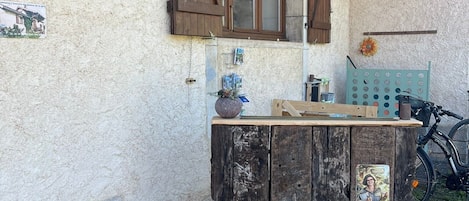 A rustic outdoor setting with a wooden table, a bicycle, and two signs indicating 'INSOLITE' and 'GÎTE' services.