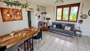 A cozy room with a wooden dining table, a sofa, and a large window with a view.