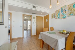 A dining area with a table set for two, a wooden door, and abstract wall art.