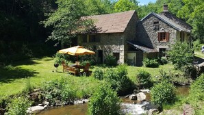 A stone house with a garden and a stream. - Cottage "Le Moulin de Laval" with Private Terrace, Wi-Fi, and Air Conditioning (Saint-Priest-des-Champs)