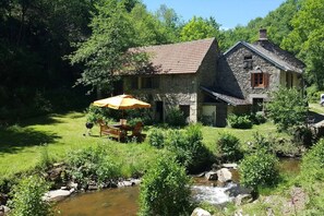 A stone house with a garden and a stream. - Cottage "Le Moulin de Laval" with Private Terrace, Wi-Fi, and Air Conditioning (Saint-Priest-des-Champs)