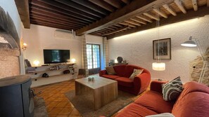 A cozy living room with a television, sofa, and coffee table. - Cottage "Le Moulin de Laval" with Private Terrace, Wi-Fi, and Air Conditioning (Saint-Priest-des-Champs)